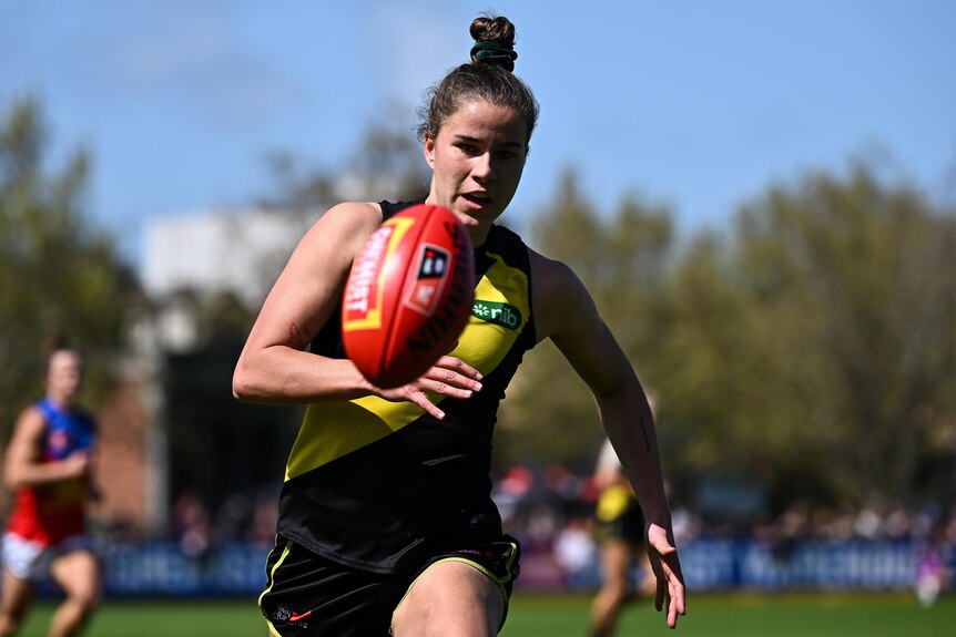 A Richmond AFLW player chases the ball during a match.