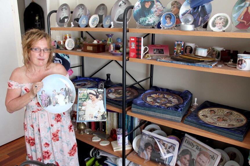 Woman stands holding plate with image of Princess Diana and surround by other royal memorabilia.