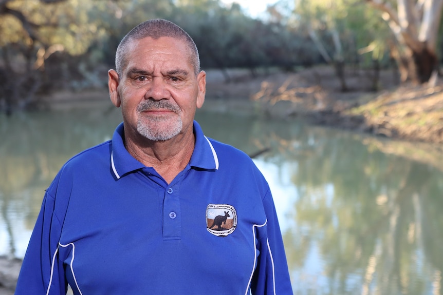 Fred Hooper, wearing a blue shirt, standing in front a creek