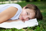 Happy woman alone lying on grass in park