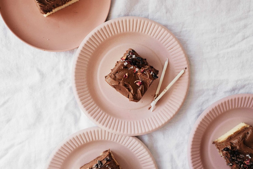 Four slices of cake with chocolate hazelnut icing, dried rose petals and sea salt with birthday candles, to share.