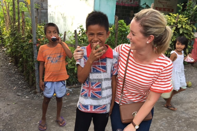 Jane Norman with a child on a visit to the seaside village of Barangay Tapian.