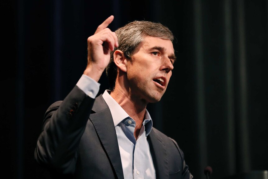 Beto O'Rourke, wearing a suit, gestures with his right hand while speaking.