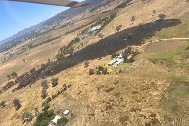 A photograph taken by a plane of scorched black fields adjacent some buildings
