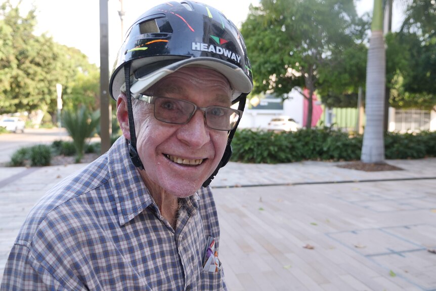 A man smiling in a bike helmet and glasses
