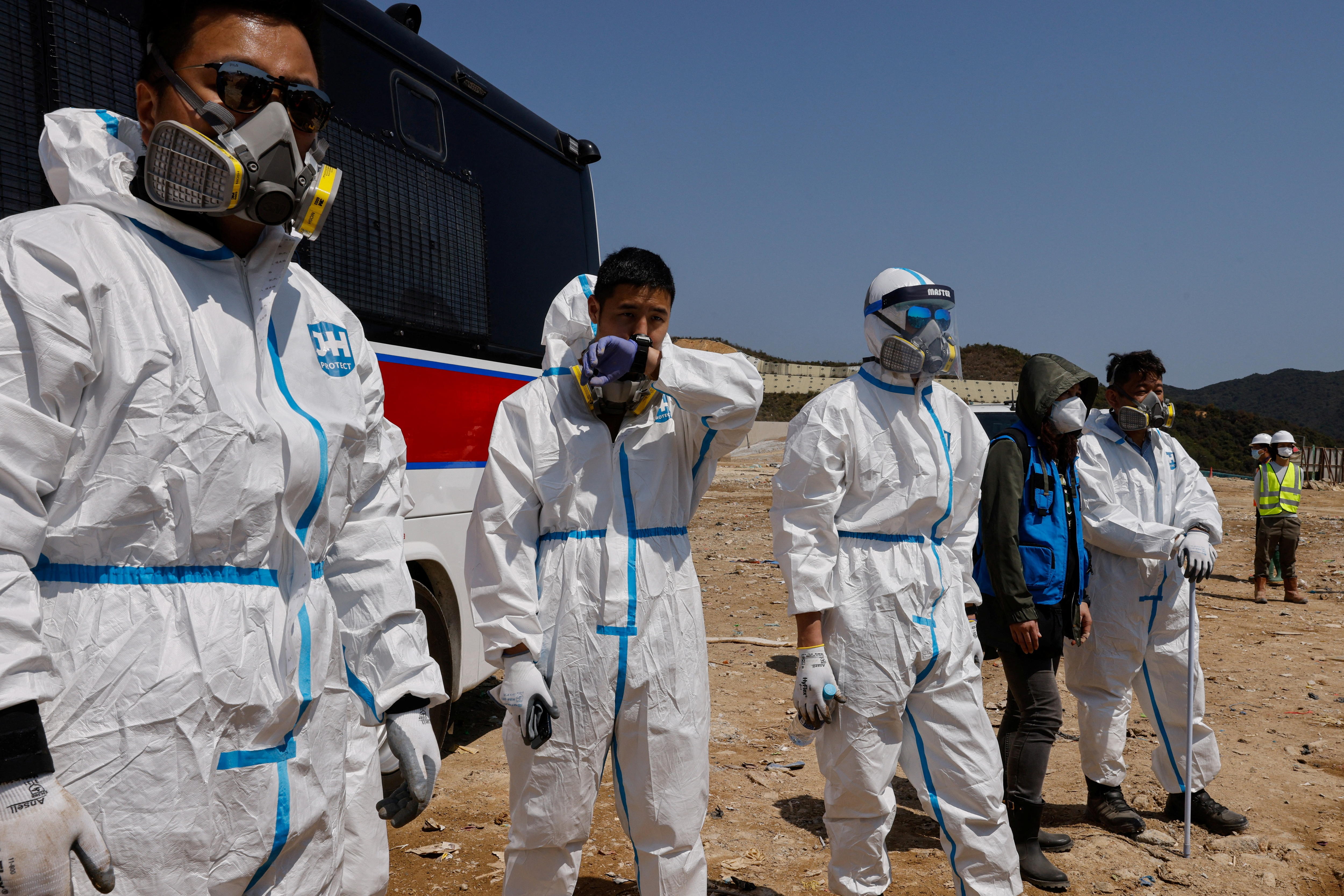 Four men in white protective suits and masks