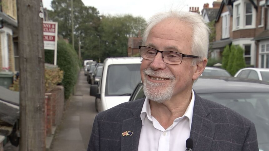 A head and shoulders  shot of a smiling, grey-haried man with a goatie.