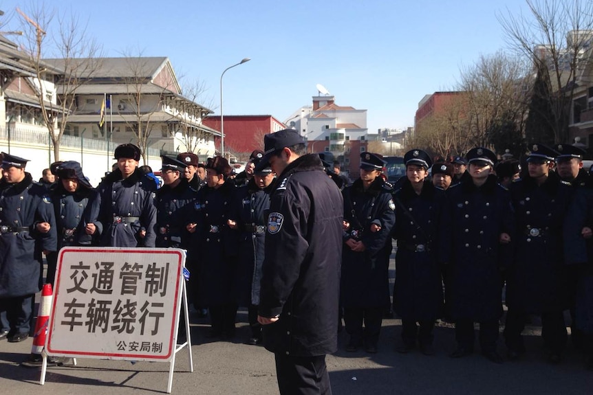 Chinese police gather outside the Malaysian embassy in Beijing as relatives of MH370 passengers protest
