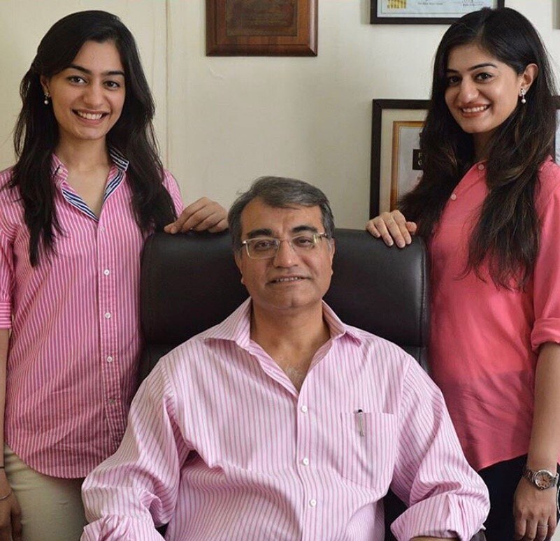 two daughters stand with their father