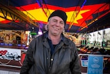 Elwin Bell sits in front of a dodgem car ride.