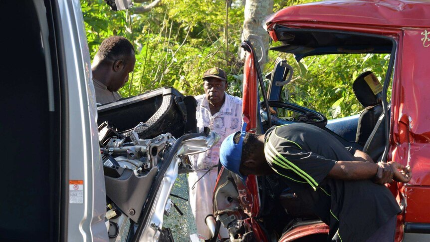 Men inspect head-on Port Vila crash aftermath