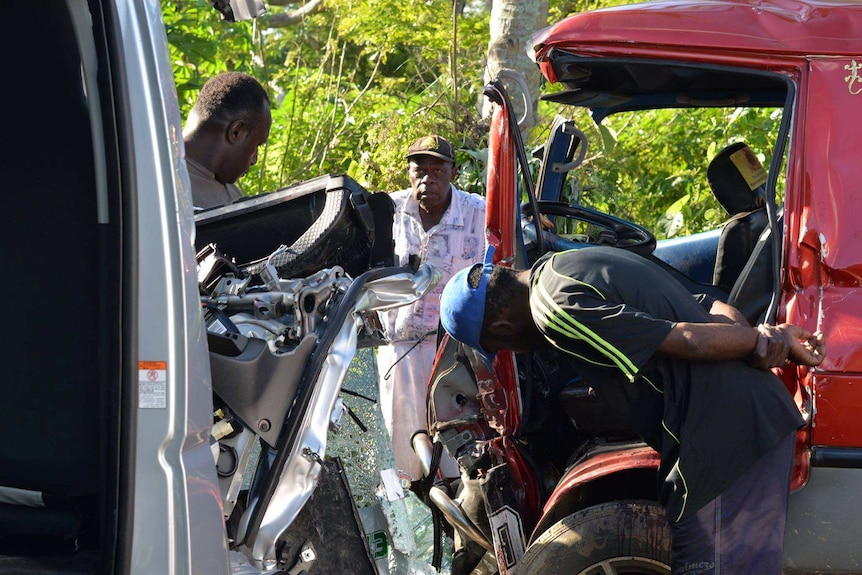 Men inspect head-on Port Vila crash aftermath