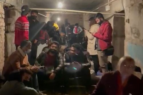 A group of Indian people sitting inside a dark basement 