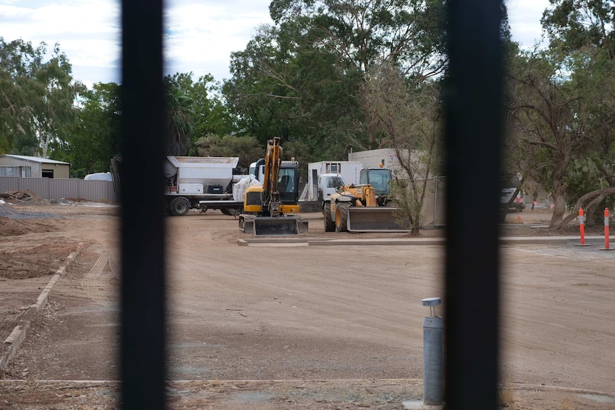 Building equipment as seen through bars on a fence.