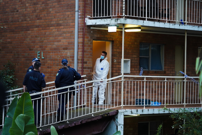Police standing outside an apartment with tape.