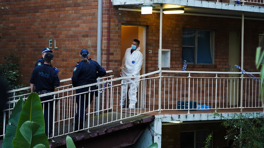 Police standing outside an apartment with tape.