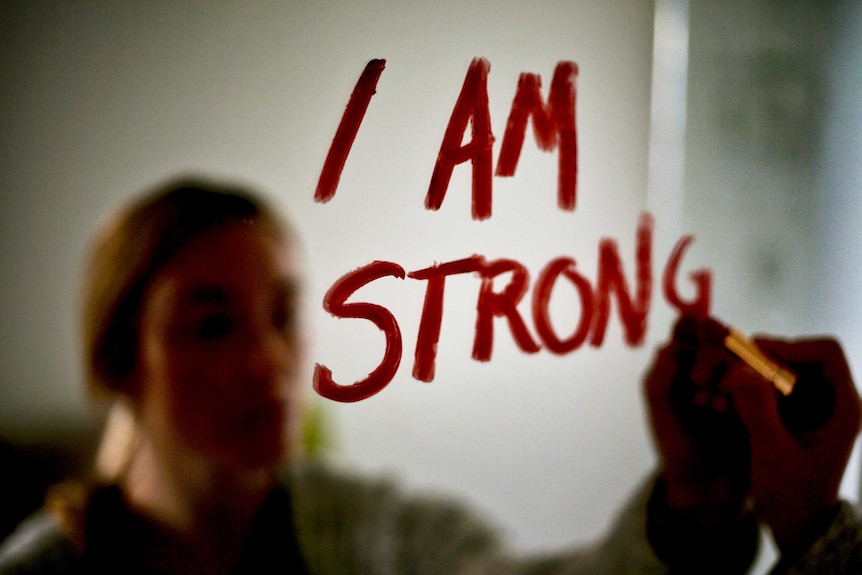 the words 'I am strong' written on a mirror
