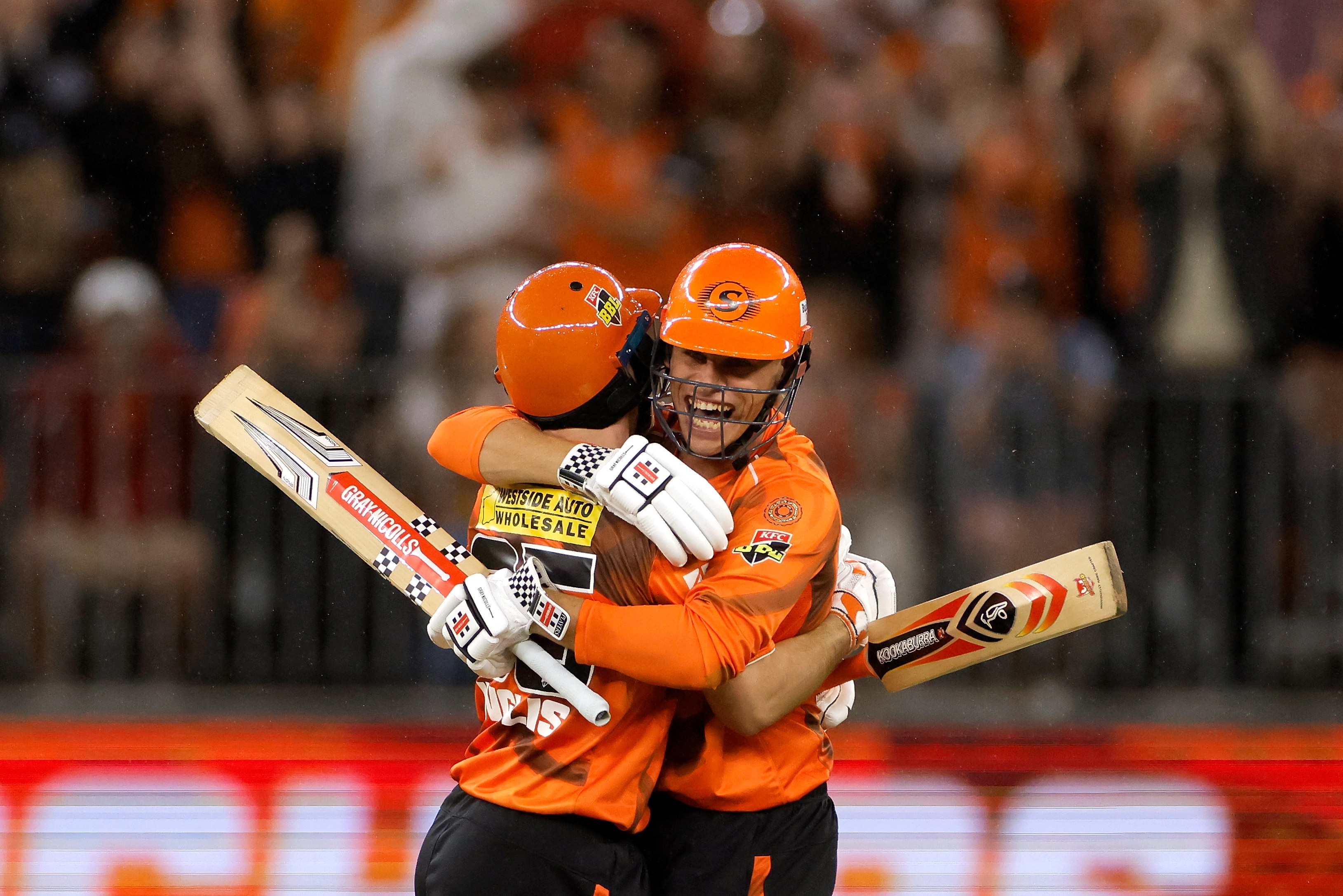 Dois batedores do Perth Scorchers se abraçam após vencer um jogo. 