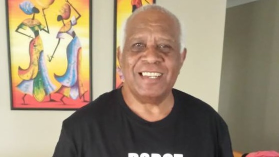 A smiling older man wearing a dark shirt.