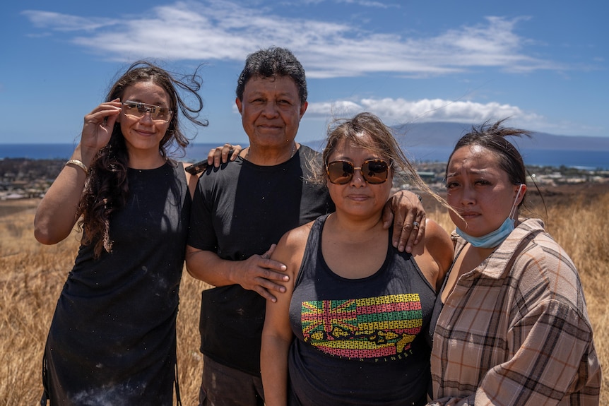 Kiana, Ruben, Suzette and Naz Navarro are standing on dry grass. The town is in the distance behind them.