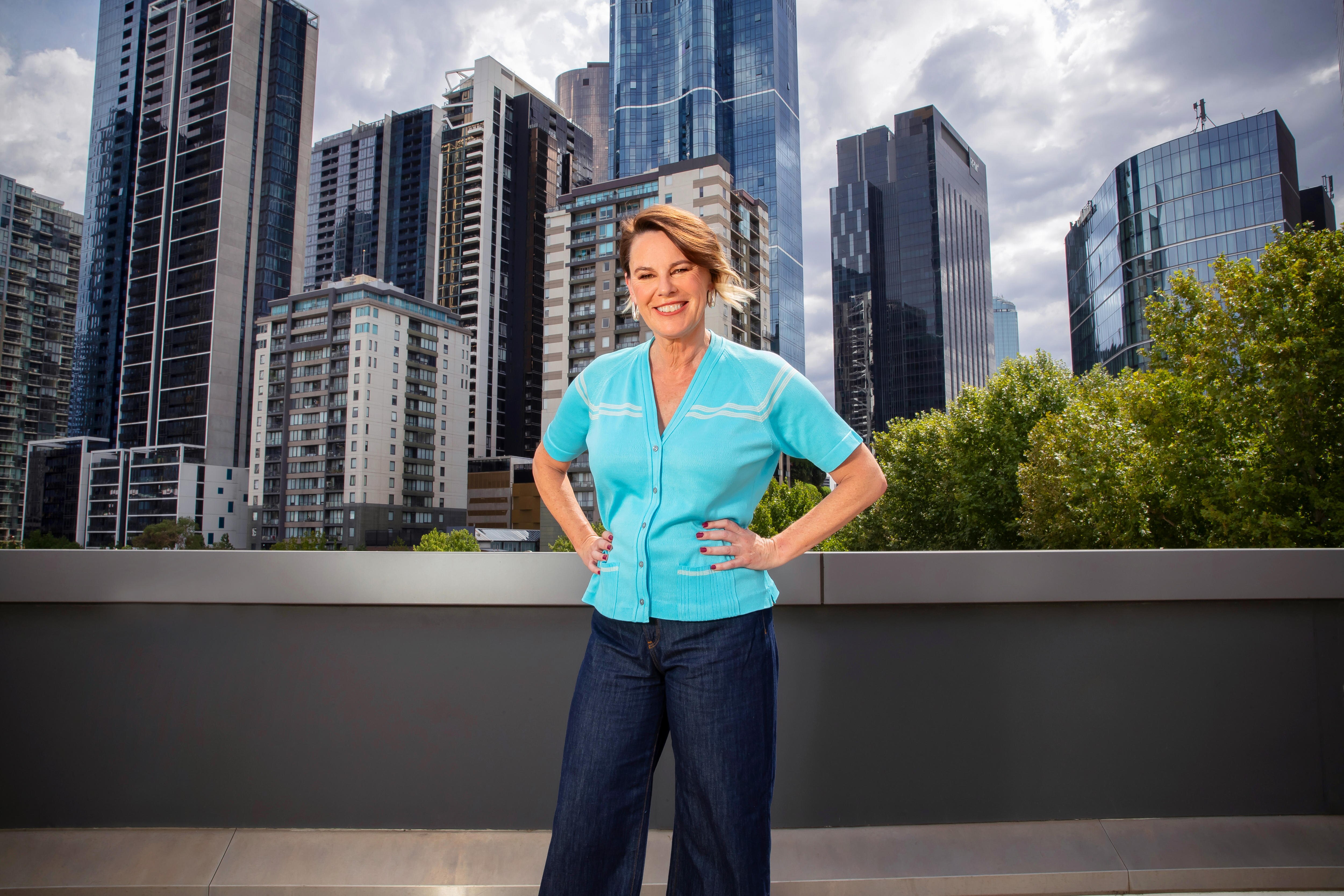 Mary Gearin, standing on a terrace, with the Melbourne skyline behind her.
