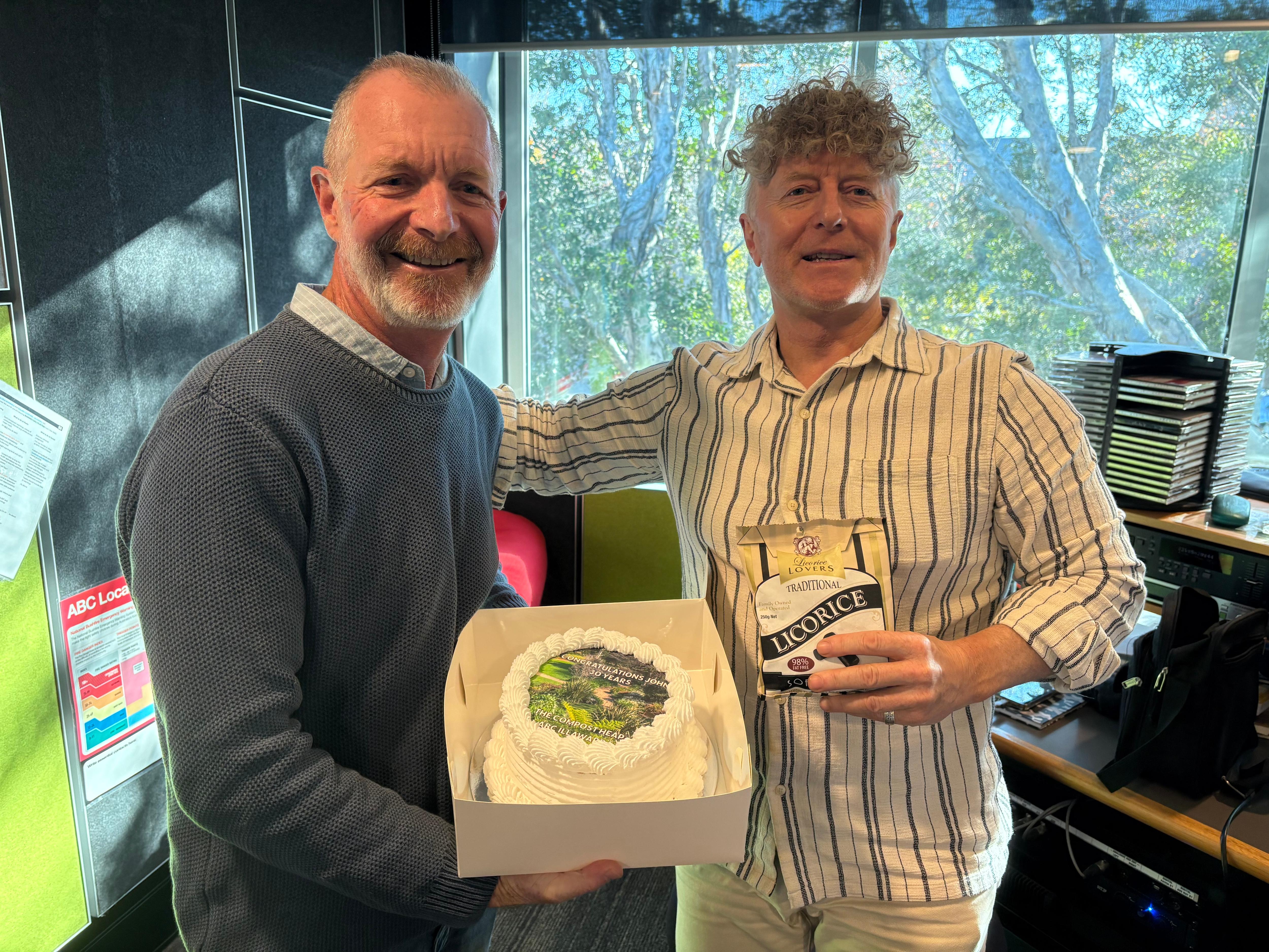 Photo of a man giving another man a cake that says happy 30 years on it