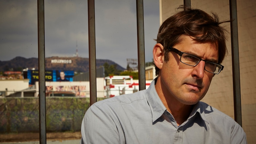 Louis Theroux standing in front of a fence