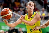 An Australian Opals player holds the basketball as a New Zealand opponent defends.