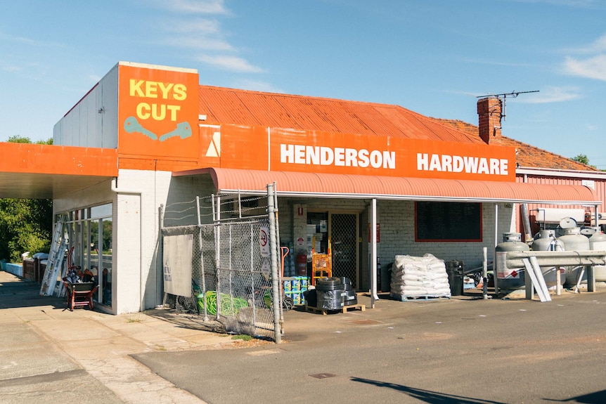An orange-roofed building with 'Henderson Hardware' and 'keys cut' on a sign on the roof.
