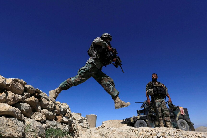 A member of Afghanistan's Special Forces unit jumps from a wall during patrol near Achin village.