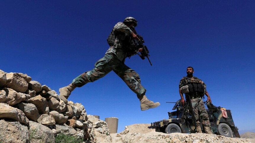 A member of Afghanistan's Special Forces unit jumps from a wall during patrol near Achin village.
