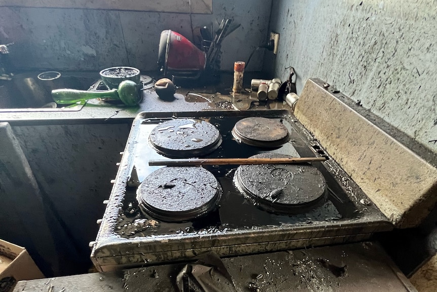 A stovetop is covered in thick black oil from a spill cause by damage from floods in Broadwater New South Wales.