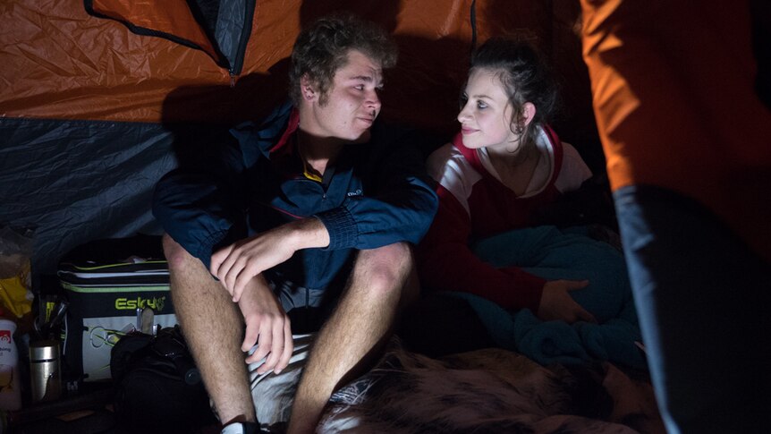 Young couple sititng inside their tent at night