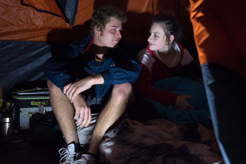 Young couple sititng inside their tent at night