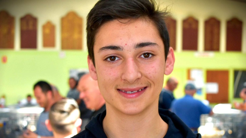 A 15-year-old boy smiles at a pigeon auction.