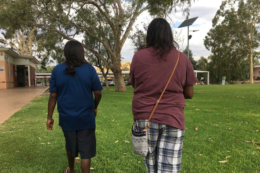 Two Aboriginal women walk away from the camera.