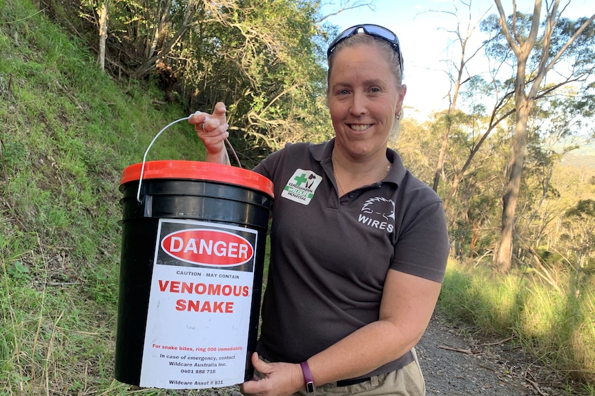 Amy Wregg holding a bucket with the label "Venomous Snake"