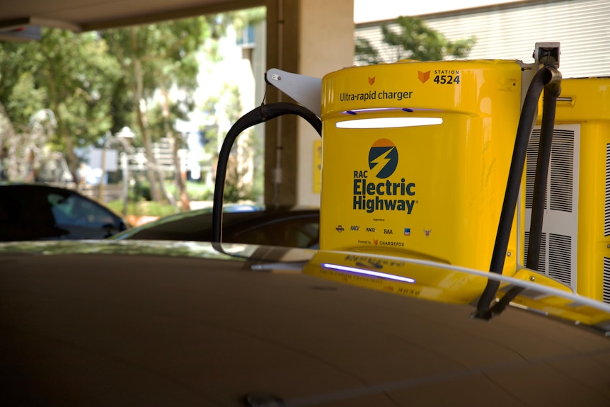 A yellow electric charger plugged into a black car