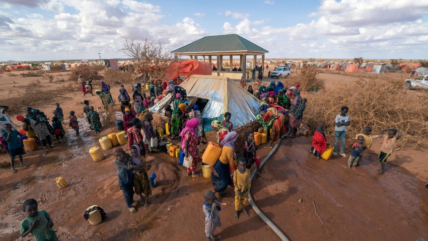 people gather around where water is being distributed in a camp in Somalia