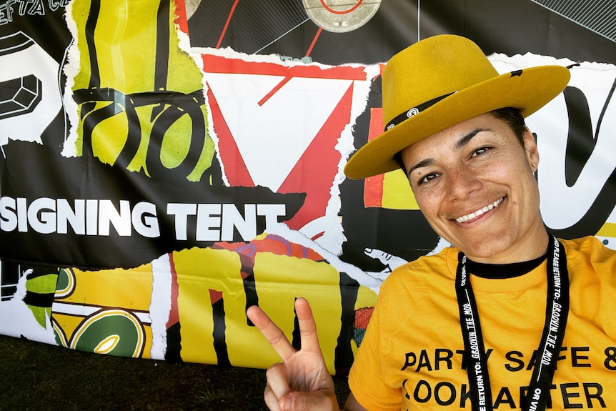 Woman in yellow shirt and yellow hat taking a selfie.