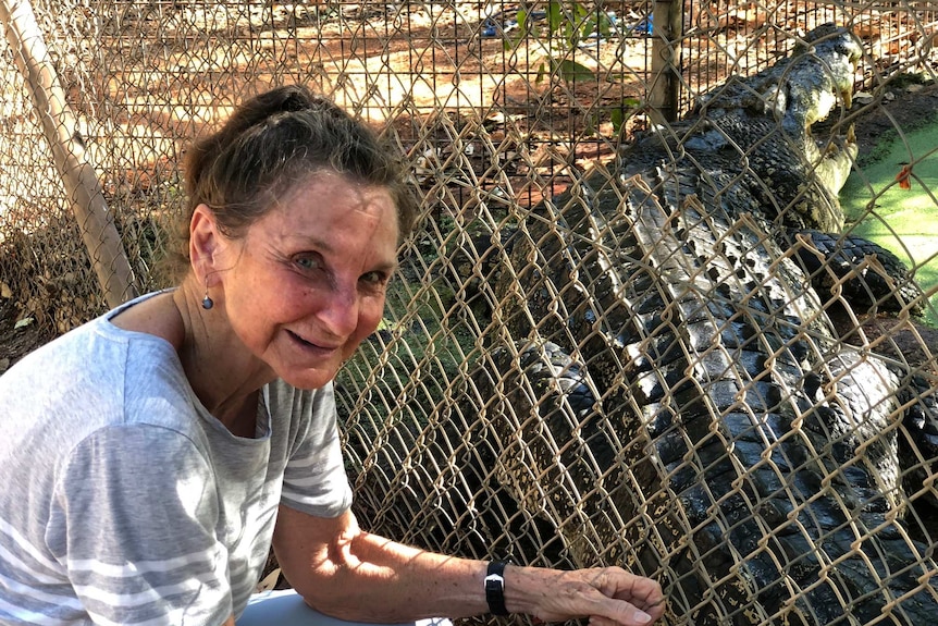 Val Douglas crouches next to a wire fence with One Eyed Willie on the other side.