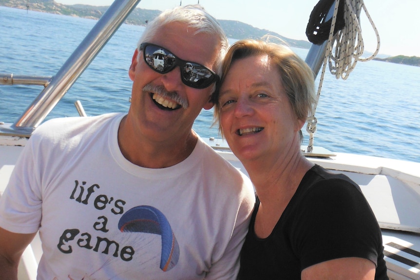 A middle-aged man and woman smile on a boat.