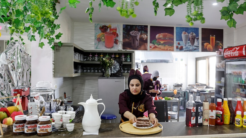 A woman in a diner placing a cake onto a serving tray