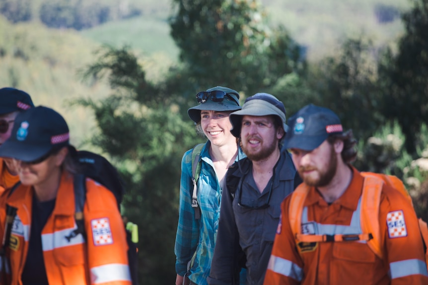 A man smiles walking alongside other men in orange shirts