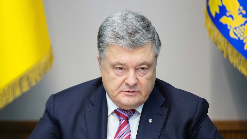 Ukrainian President Petro Poroshenko sits at a meeting in between two flags