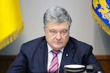 Ukrainian President Petro Poroshenko sits at a meeting in between two flags