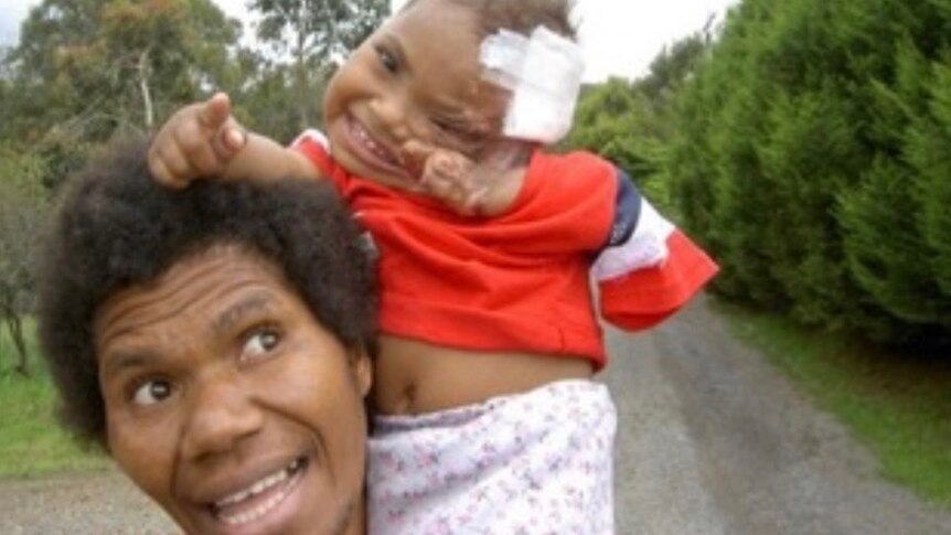 Emai as a baby sitting on her mother Elsie's shoulders.