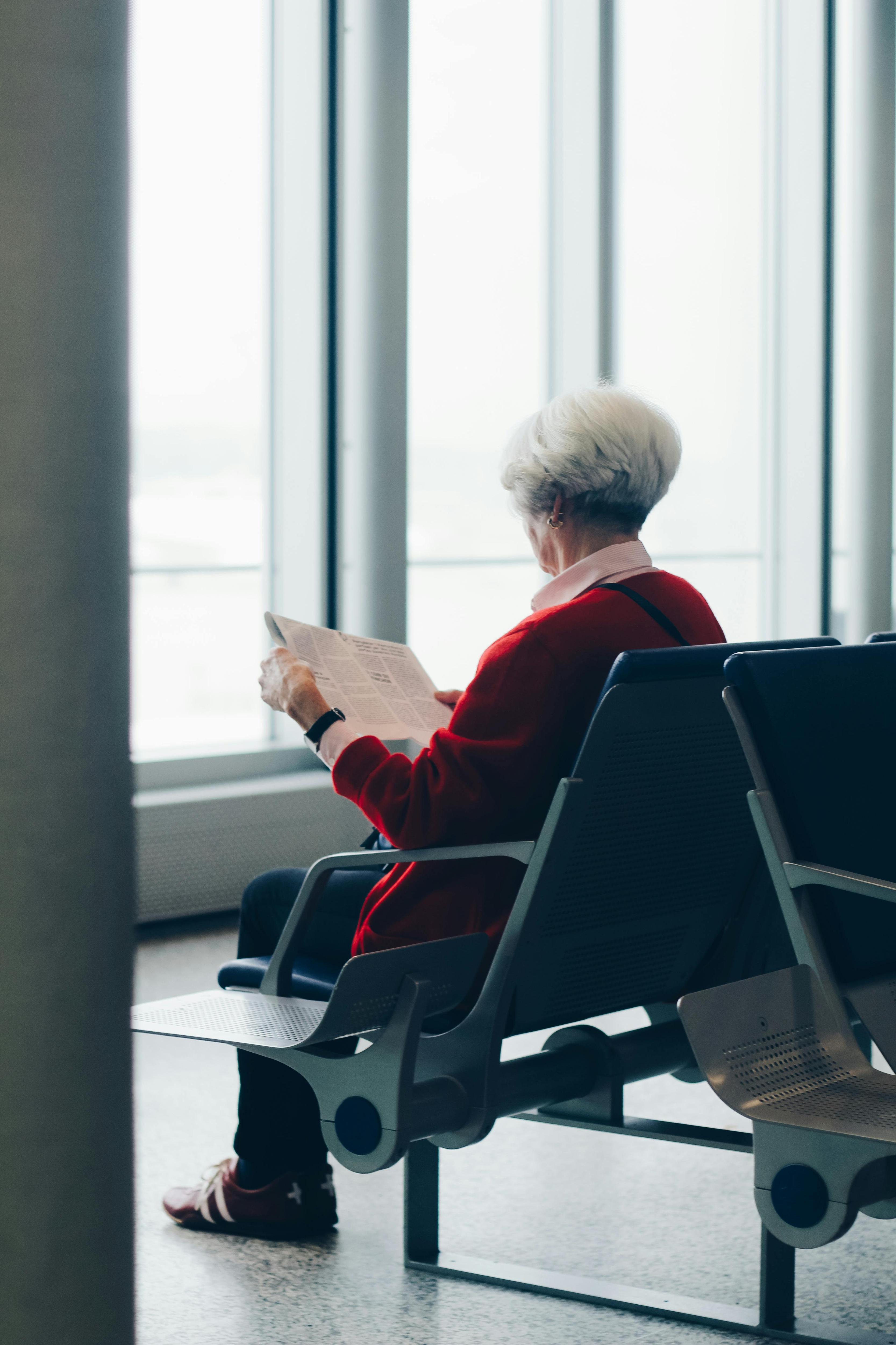A woman sits in an airport lounge reading a newspaper