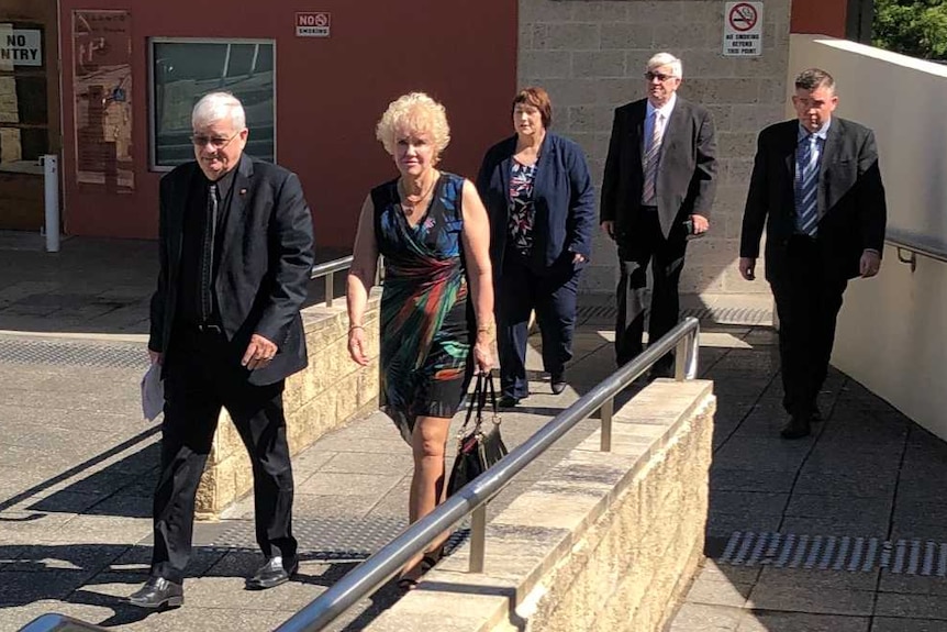 Three men in suits and two women leave the grounds of a small regional court