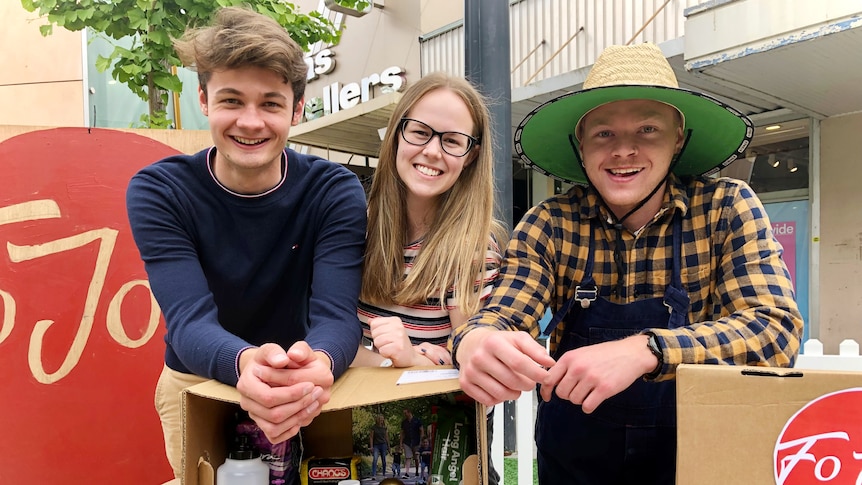 Tomas Dowler, Gemma Ritchie and Jordan Fitzgerald  lean on a box of food and smile at the camera